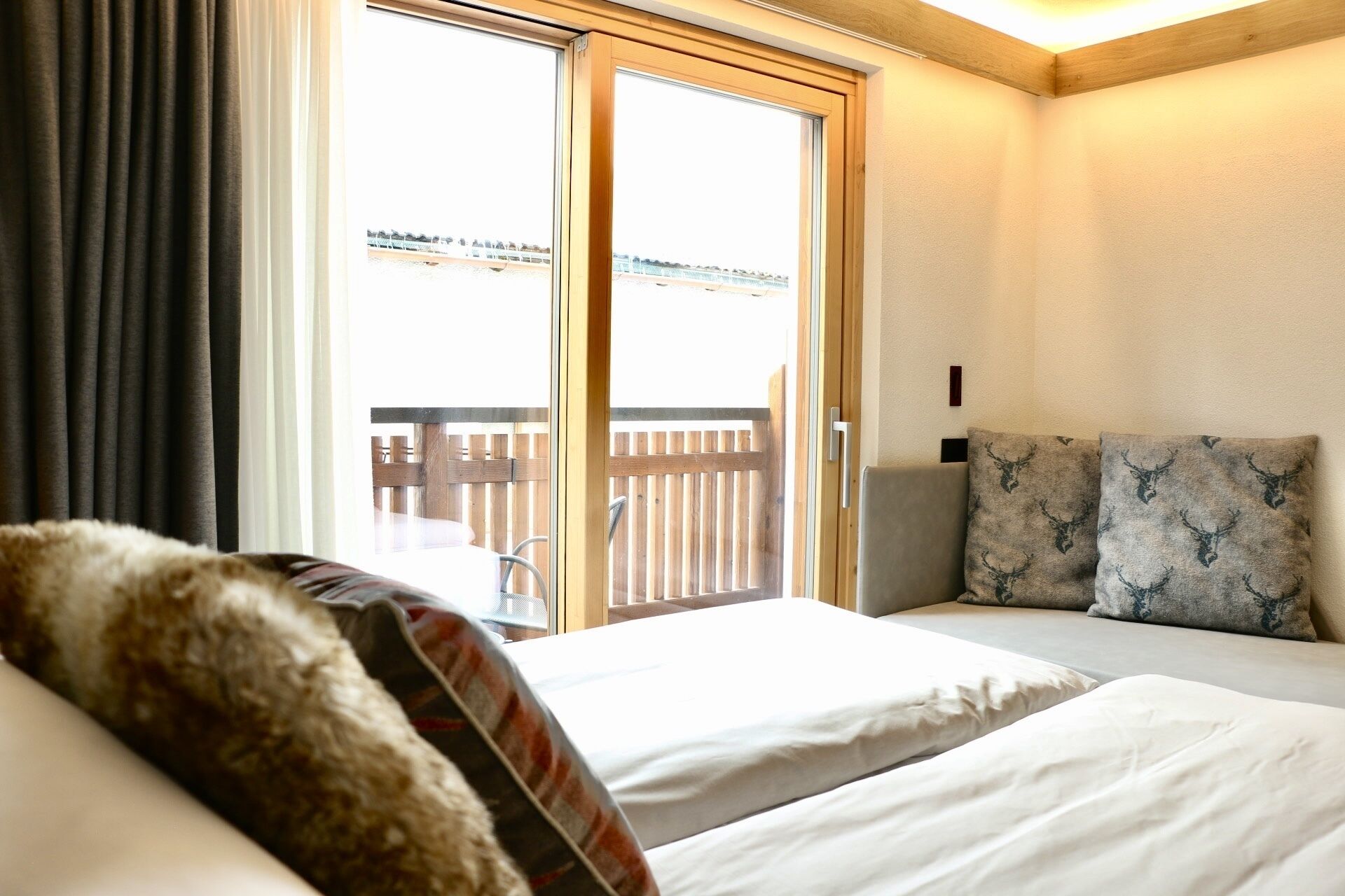 Une chambre d’hôtel avec un lit, un canapé et une vue sur une terrasse en bois à l’extérieur.