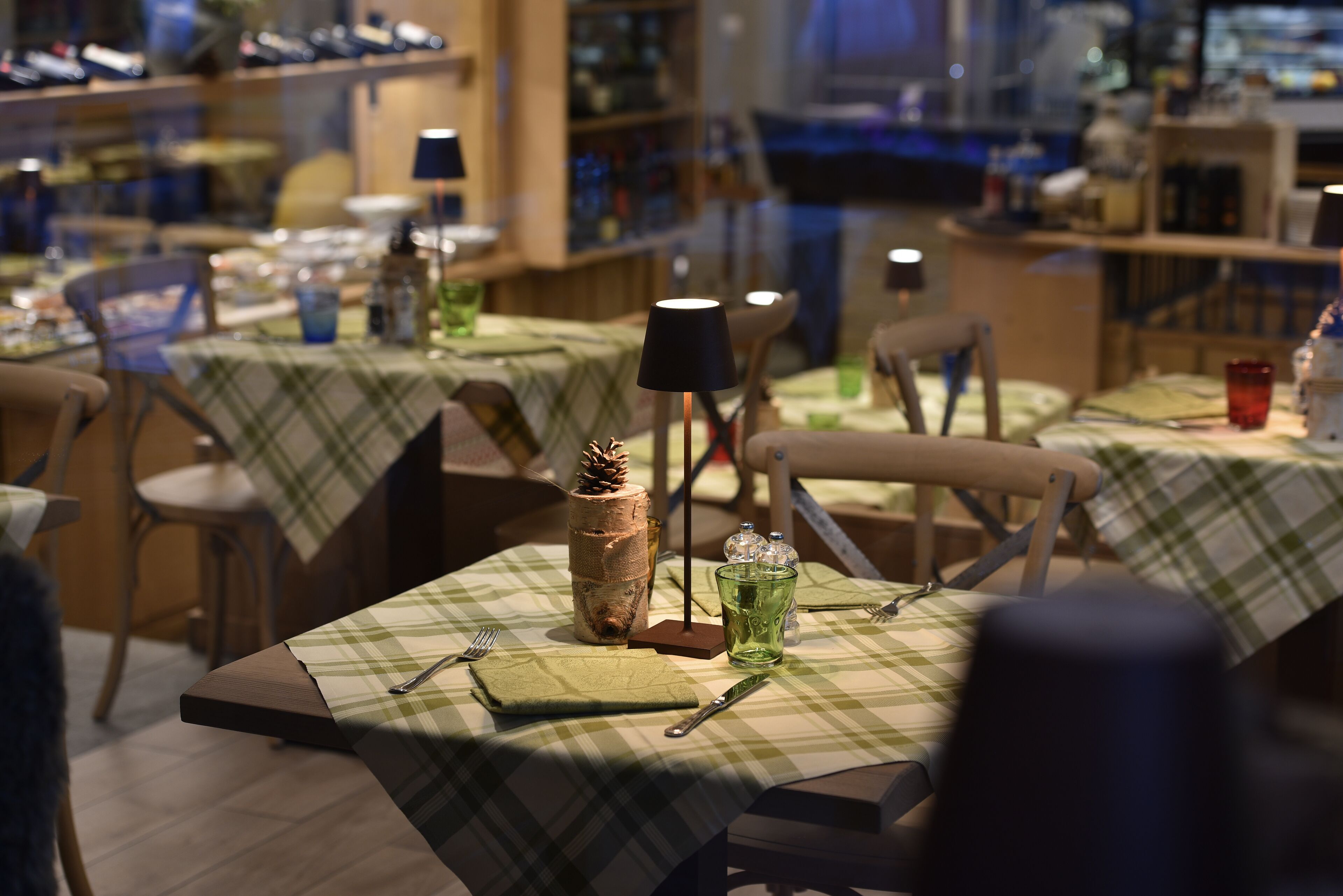 A restaurant with tables set for dining, featuring checkered tablecloths and basic table settings.