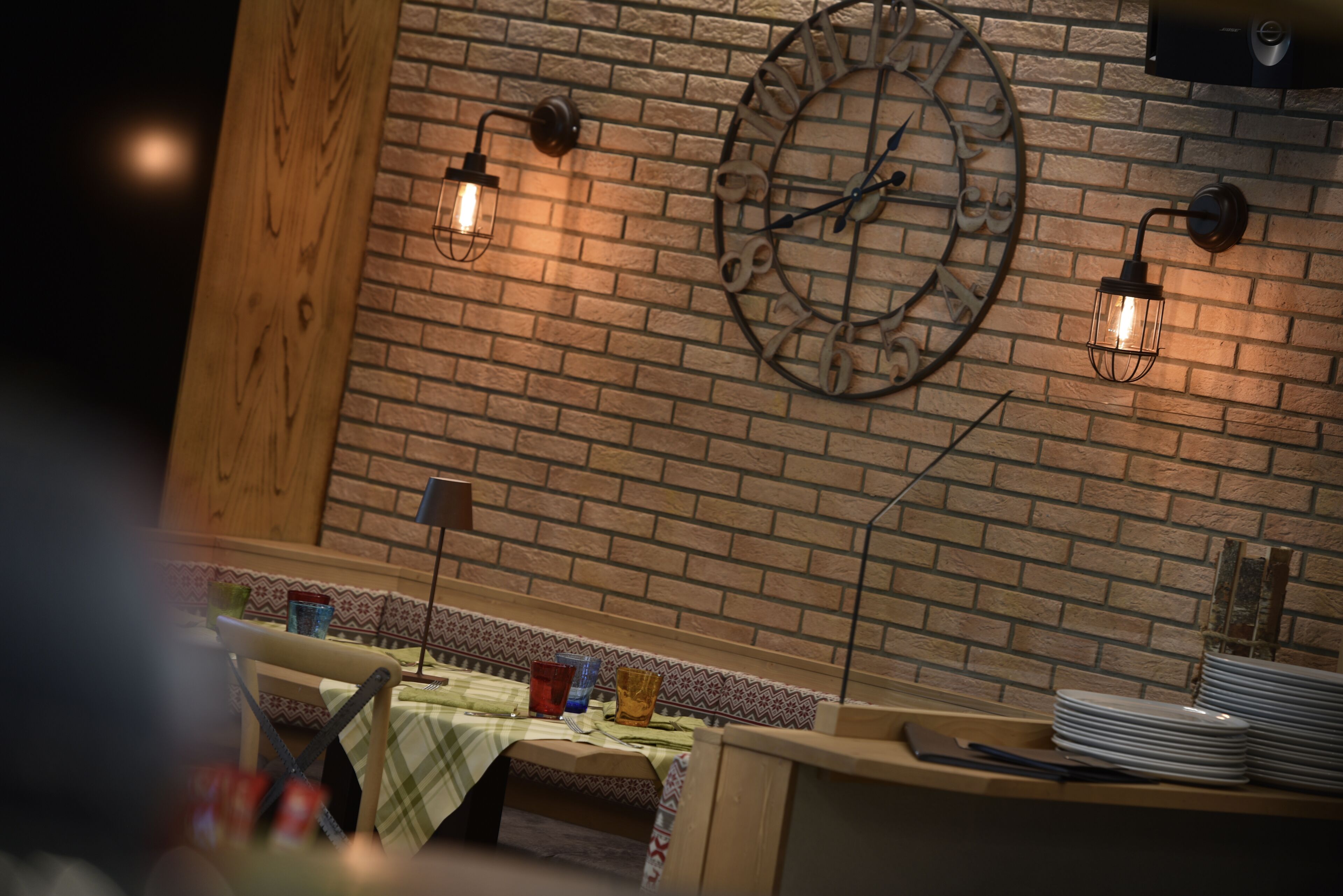 L’intérieur d’un restaurant avec un mur en briques, une horloge et deux appliques murales.