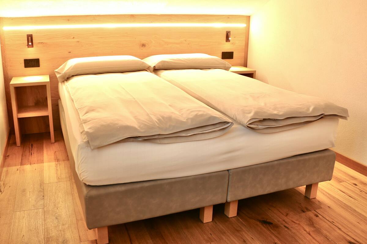 A double bed with a wooden headboard, two bedside tables, and a wooden floor.