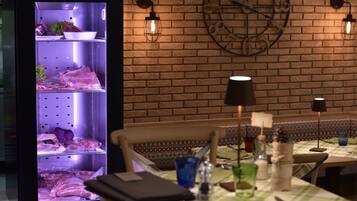 Un restaurante con pared de ladrillo, un reloj y una vitrina de comida.