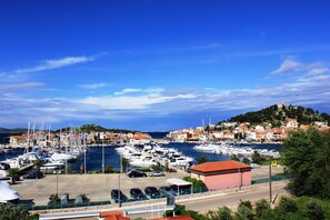 A marina with numerous boats docked, surrounded by buildings and a clear blue sky.