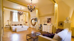 Una habitación amplia y bien iluminada con una cama grande, un sofá, una mesa de centro y un candelabro.