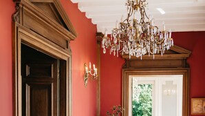 Un pasillo con suelo de cuadros, puertas de madera y un candelabro.