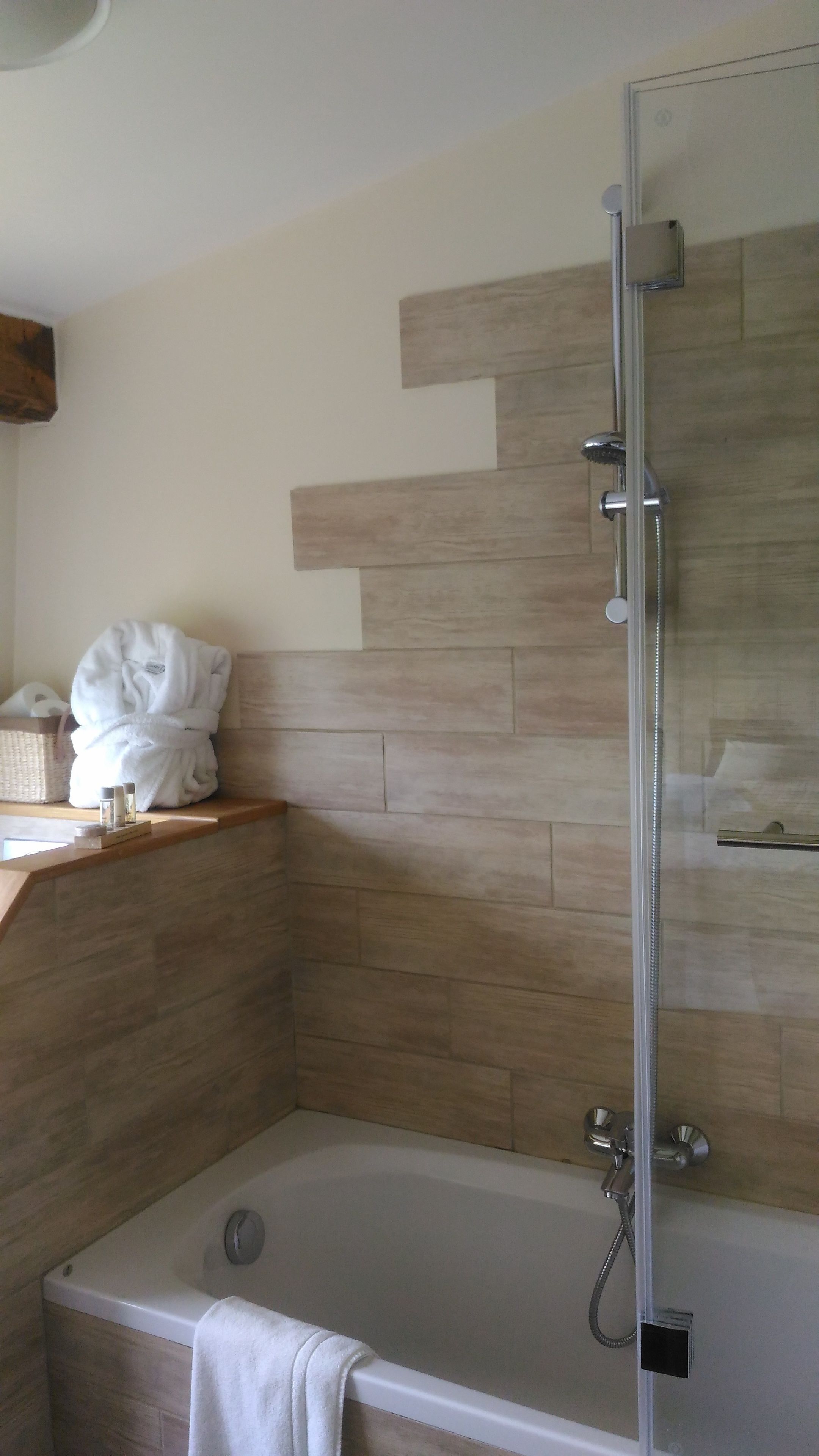 A bathroom with a bathtub, a shower with a glass door, and a towel rack with a white towel.
