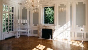 Una sala elegante con chimenea, paredes blancas decoradas y un candelabro.