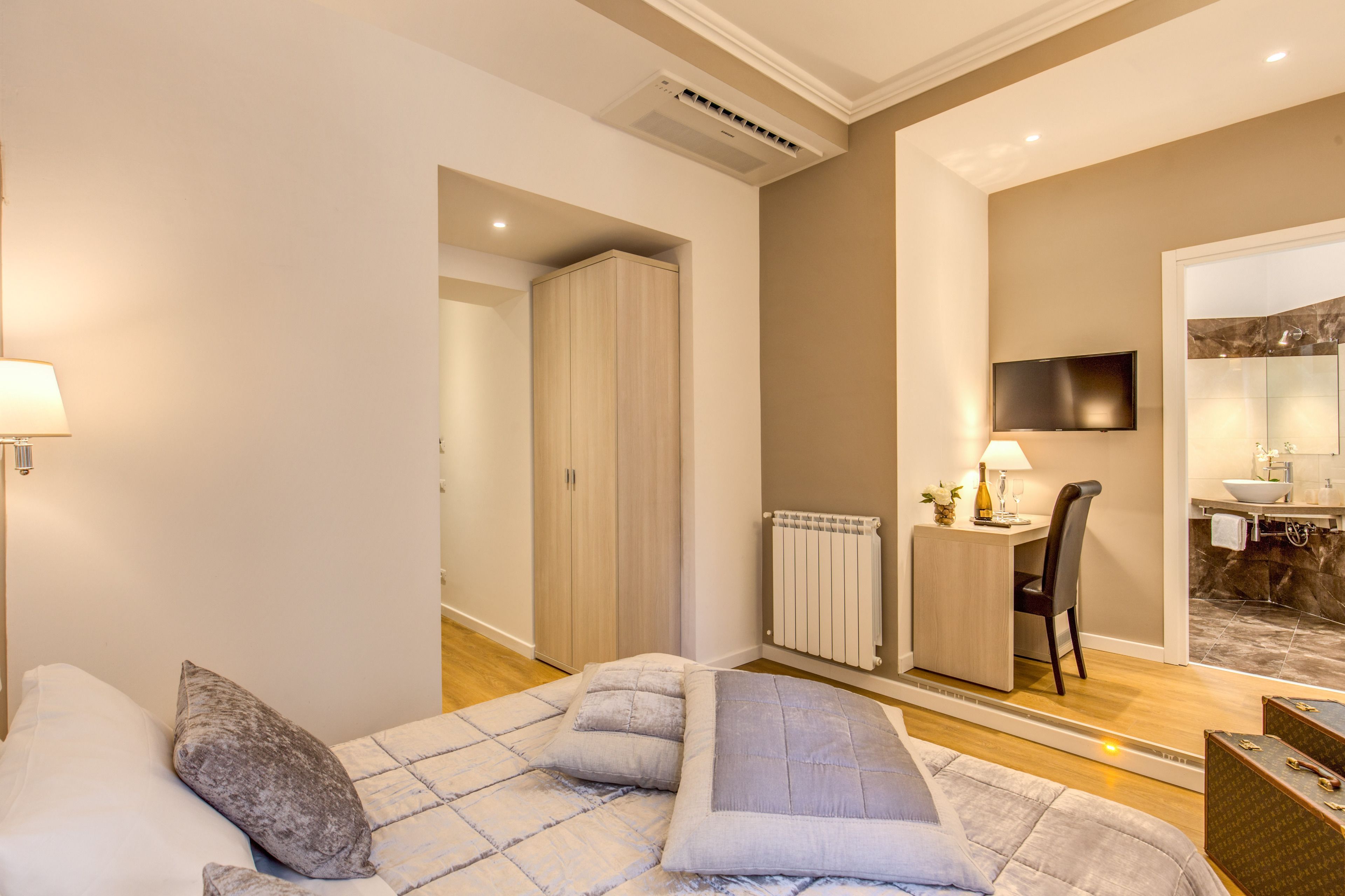 A modern bedroom with a bed, bedside table, and a desk with a chair.