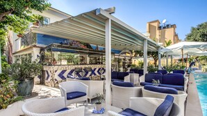 A poolside area with wicker furniture, a bar, and a covered seating area. - Hotel Florida (Sorrento)