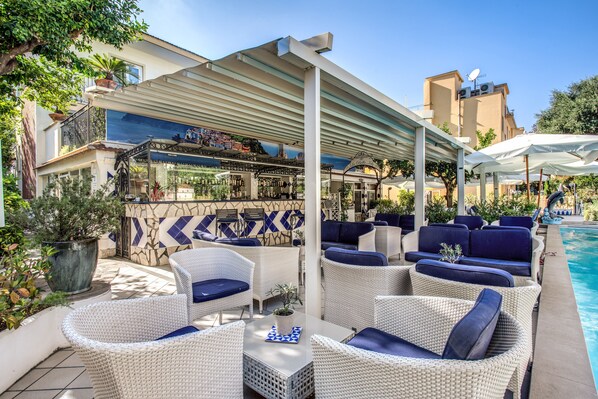 A poolside area with wicker furniture, a bar, and a covered seating area. - Hotel Florida (Sorrento)