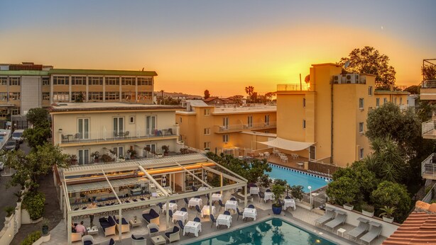 A rooftop pool area with lounge chairs and a swimming pool, surrounded by buildings and trees. - Hotel Florida (Sorrento)