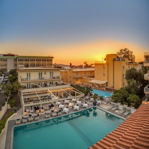A rooftop pool area with lounge chairs and a swimming pool, surrounded by buildings and trees. - Hotel Florida (Sorrento)