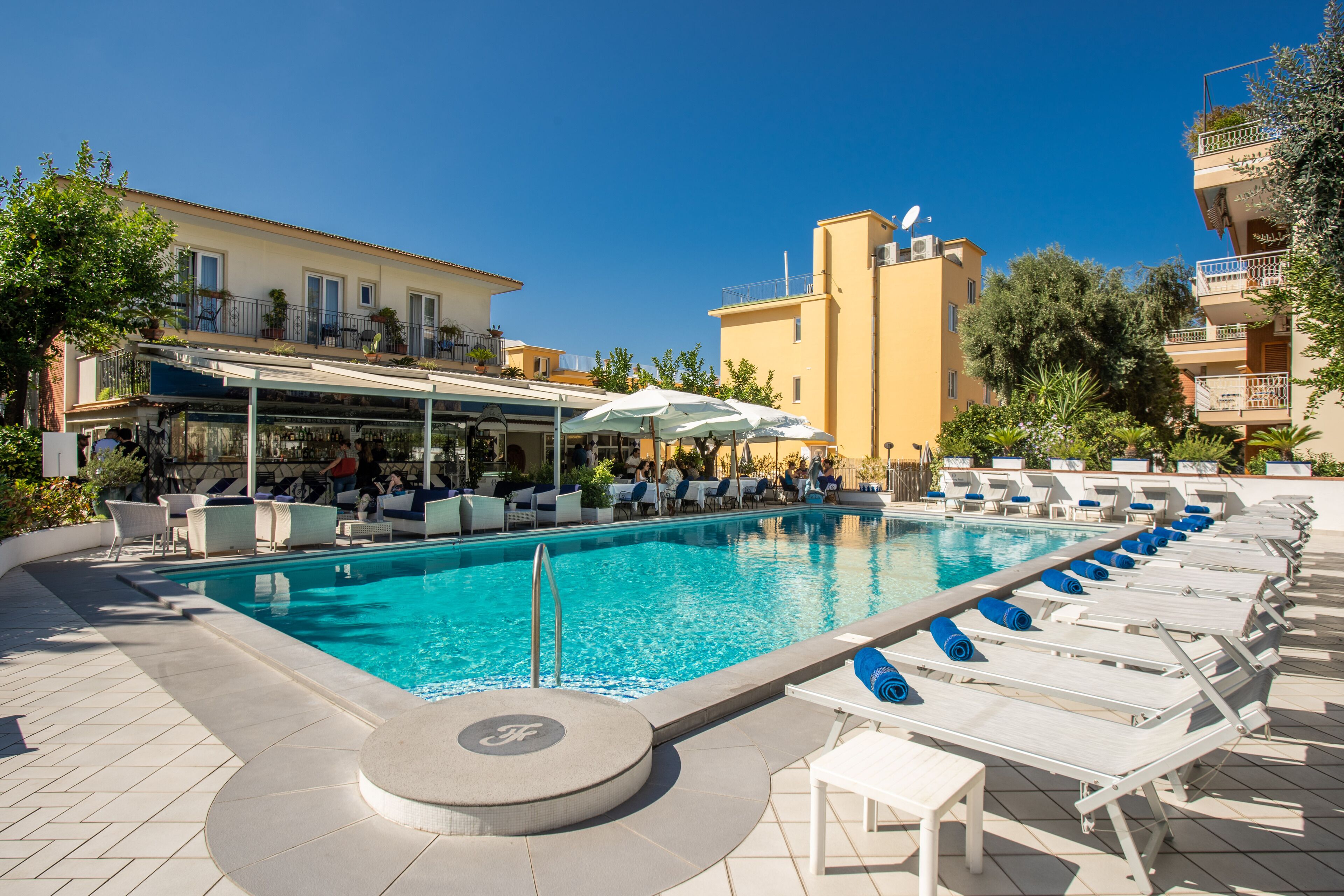 Una piscina al aire libre, sombrillas, sillones reclinables de piscina