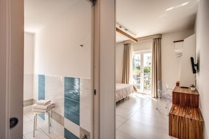 Una habitación de hotel moderna con zona de ducha, cama con vistas y un escritorio de madera.