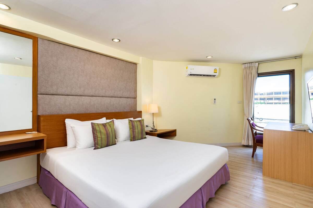 A hotel room with a large bed, bedside tables, a desk, and a chair.