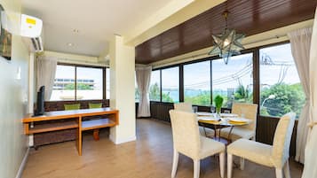 Una habitación amplia con zona de comedor, sofá y un gran ventanal con vistas al exterior.