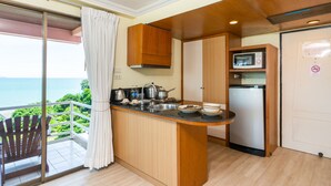 A kitchen with a view of the sea, a wooden cabinet, a microwave, and a refrigerator. - Bella Villa Metro (Pattaya)