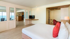 A hotel room with a large bed, a TV, a desk, and a view of the sea. - Bella Villa Metro (Pattaya)