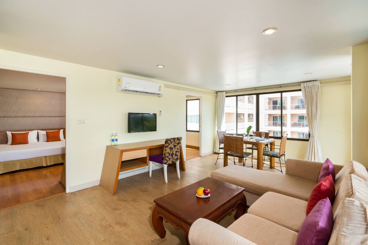 A modern living room with a sofa, a wooden coffee table, a TV, and a dining area with a table and chairs.