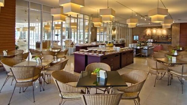Un comedor moderno con techos altos, iluminación colgante y una isla central con asientos.