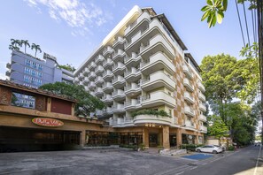 A multi-story hotel with balconies, a visible entrance, and a parking area. - Bella Villa Prima (Pattaya)