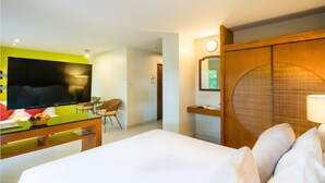 Habitación de hotel con cama, televisión, escritorio con silla y armario de madera.