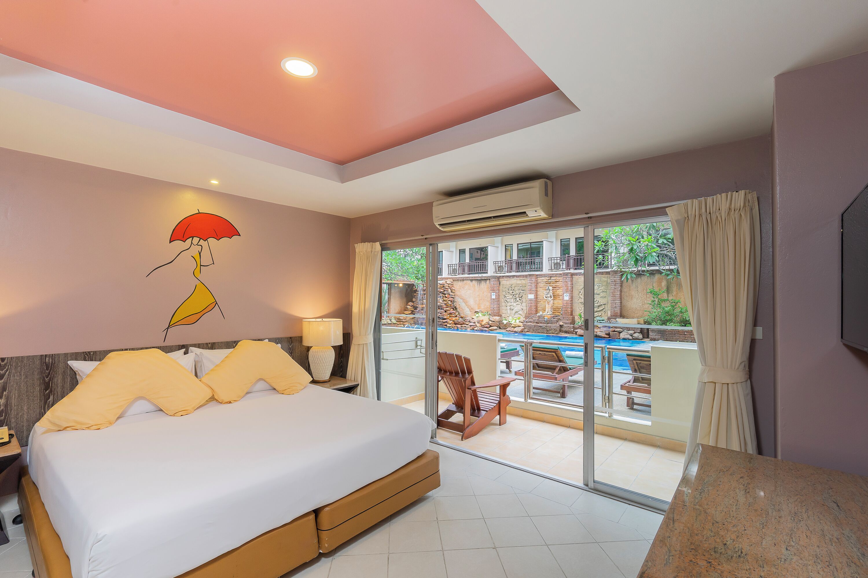 A bedroom with a bed, a nightstand, a lamp, a window with curtains, and a view of an outdoor pool area.