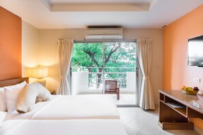 A hotel room with a bed, a nightstand, a lamp, a TV, a window with curtains, and a balcony with a chair. - Bella Villa Prima (Pattaya)