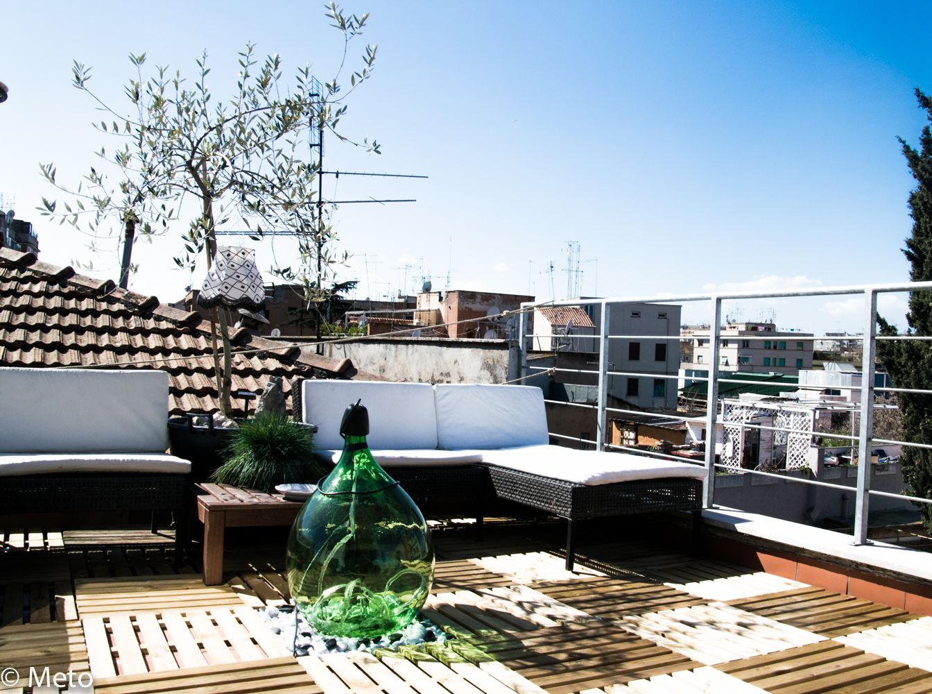 Une terrasse sur le toit, aménagée avec du mobilier d’extérieur, dotée d’une structure vitrée et offrant une vue sur le paysage urbain.