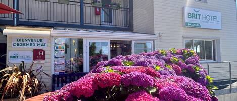 A hotel with a sign reading 'BRIT HOTEL Confort' and a welcome sign in a foreign language.