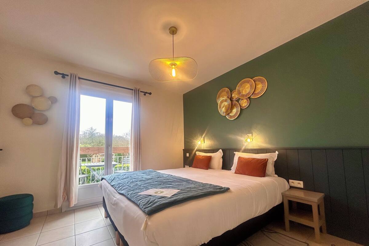 Een slaapkamer met een bed, nachtkastje, plafondlamp, uitzicht door een raam en wanddecoratie.