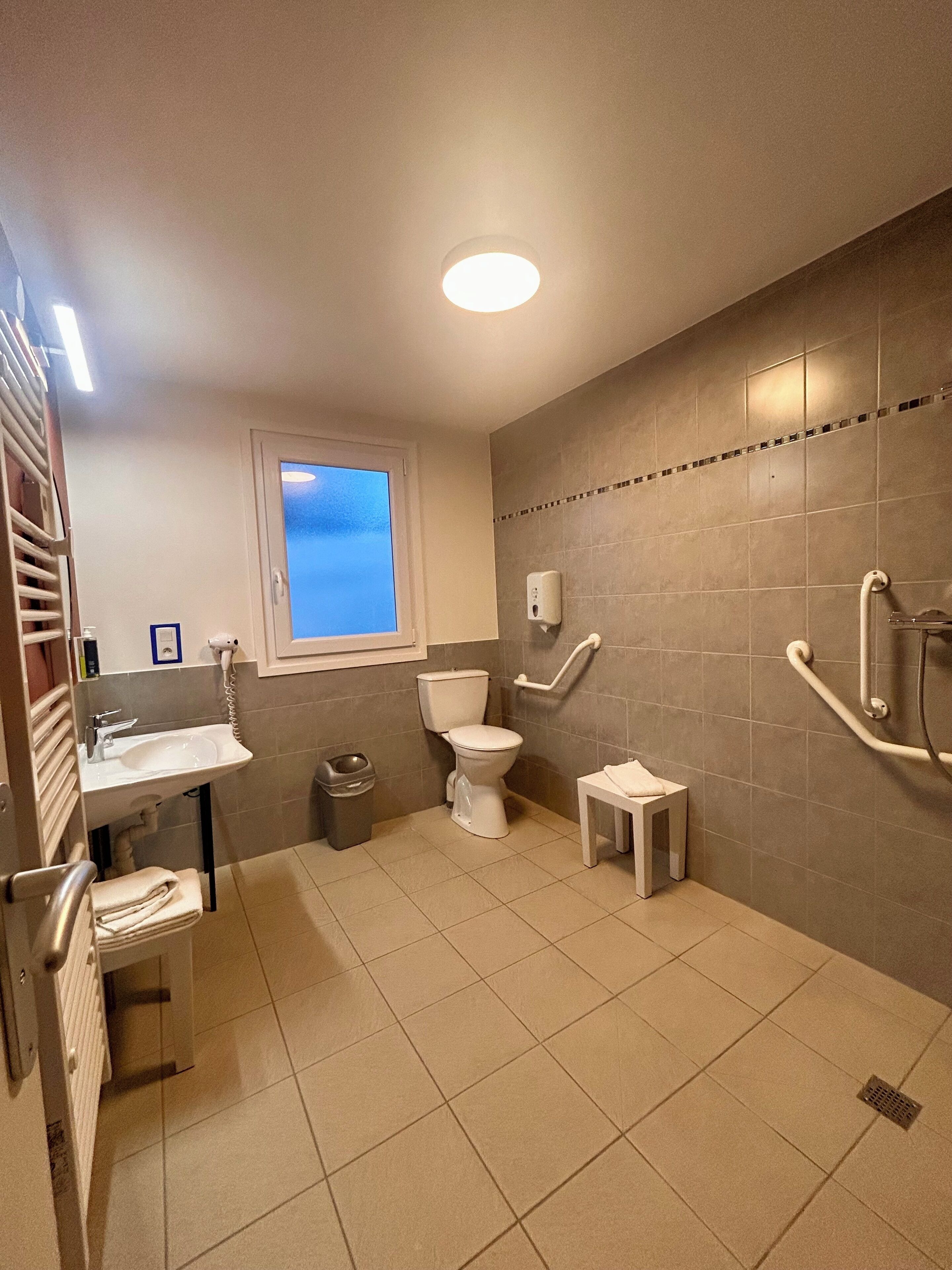 Ein modernes Badezimmer mit Toilette, Waschbecken und Händetrockner.