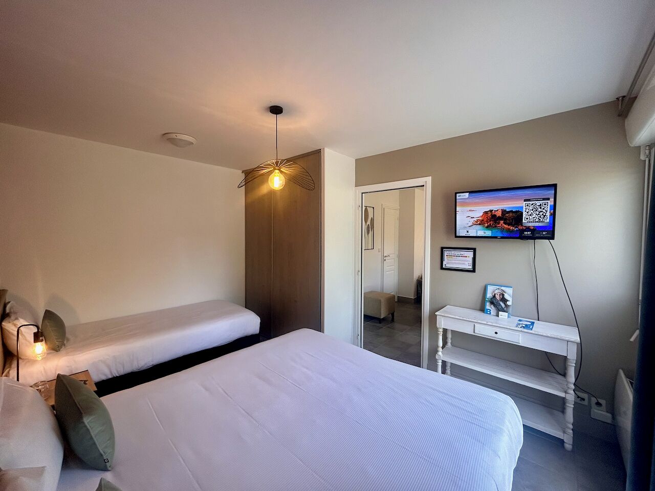 Un dormitorio con cama, escritorio, televisor y luz de techo.