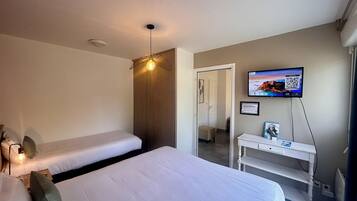 Un dormitorio con cama, escritorio, televisor y luz de techo.