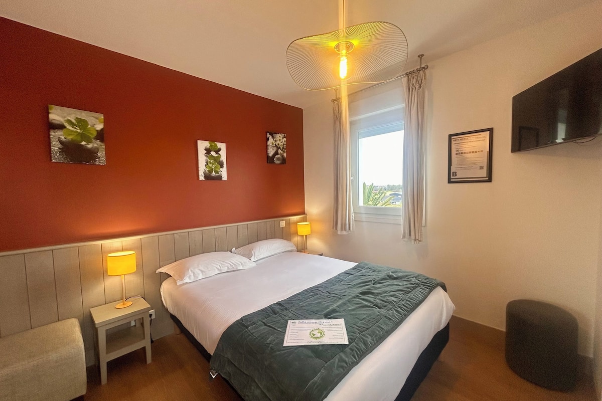 Hotelkamer met een bed, nachtlampjes, een raam met gordijnen en decoratie aan de muur.