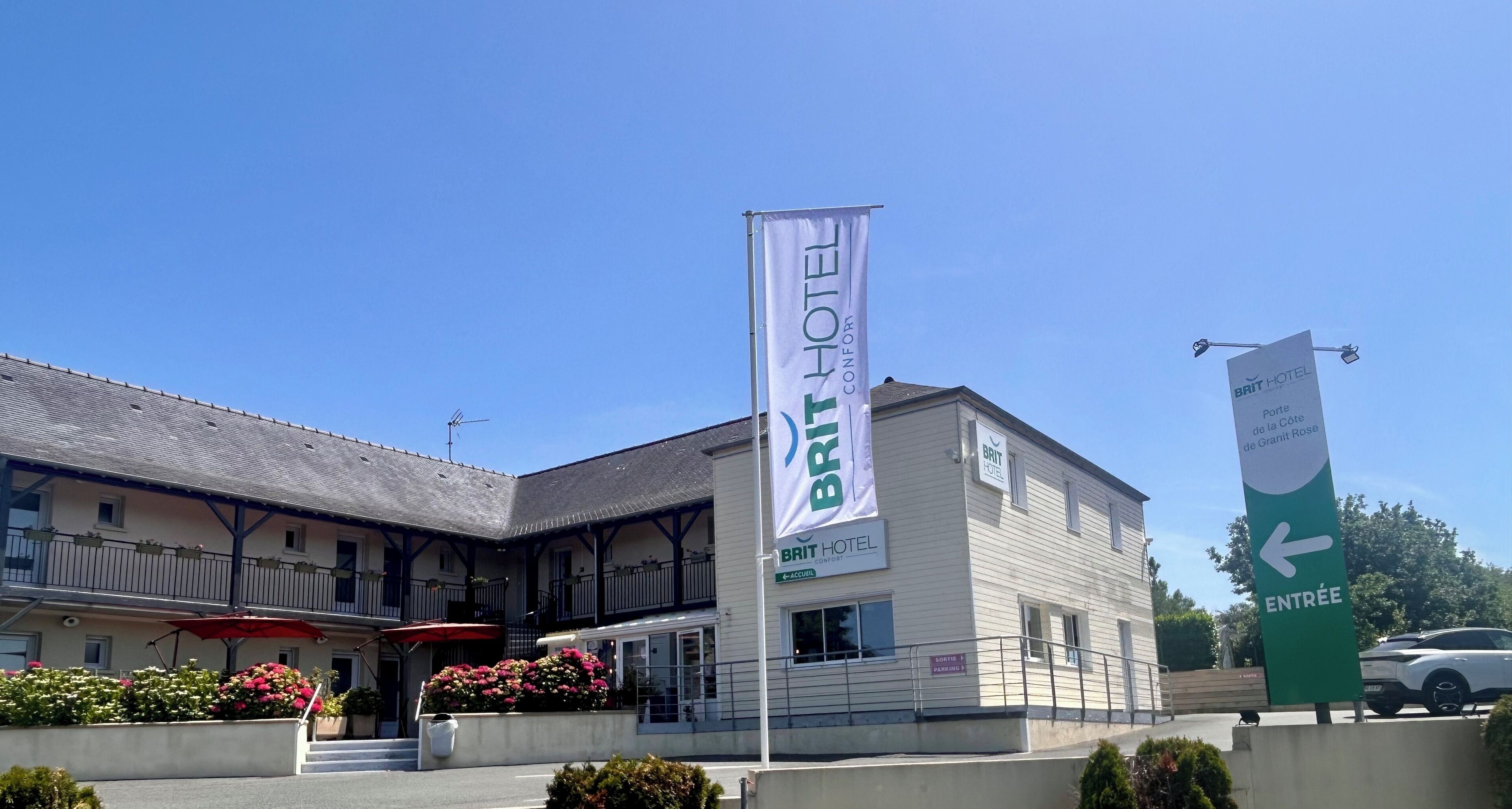 A hotel with a prominent Brit Hotel sign, a balcony with outdoor seating, and a green entrance sign.