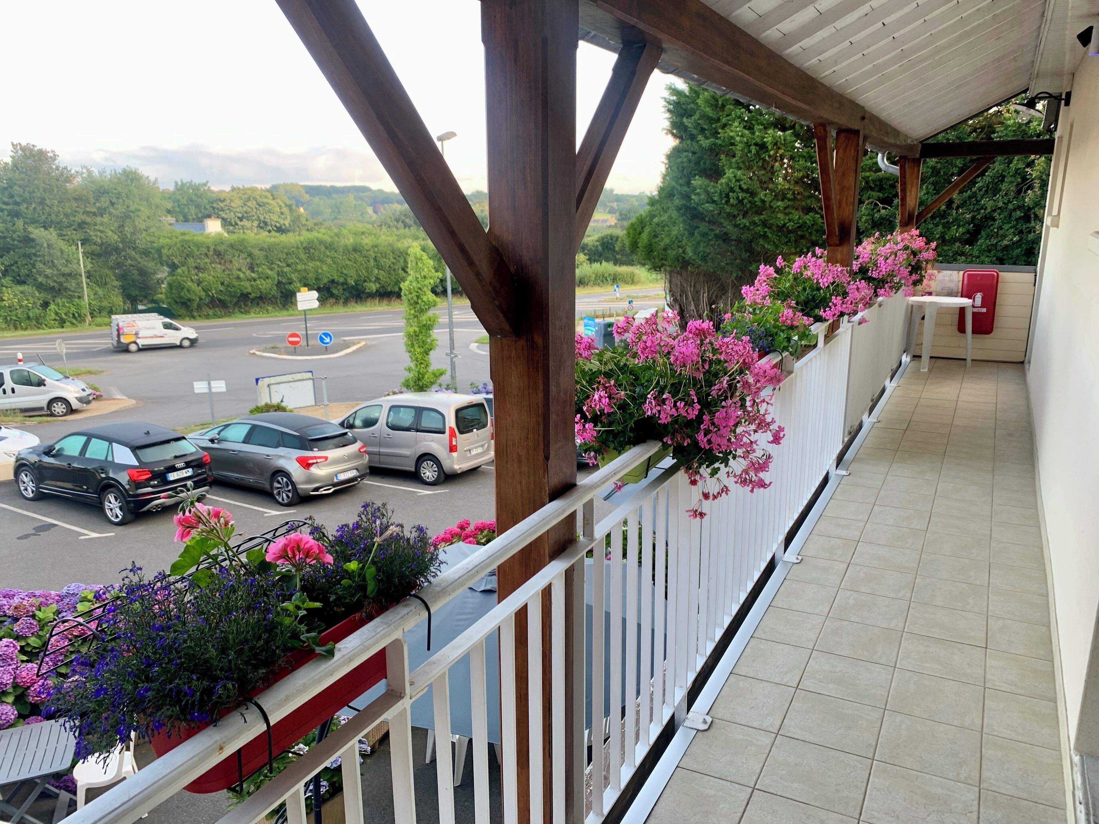 A balcony with a view of a parking lot and greenery.