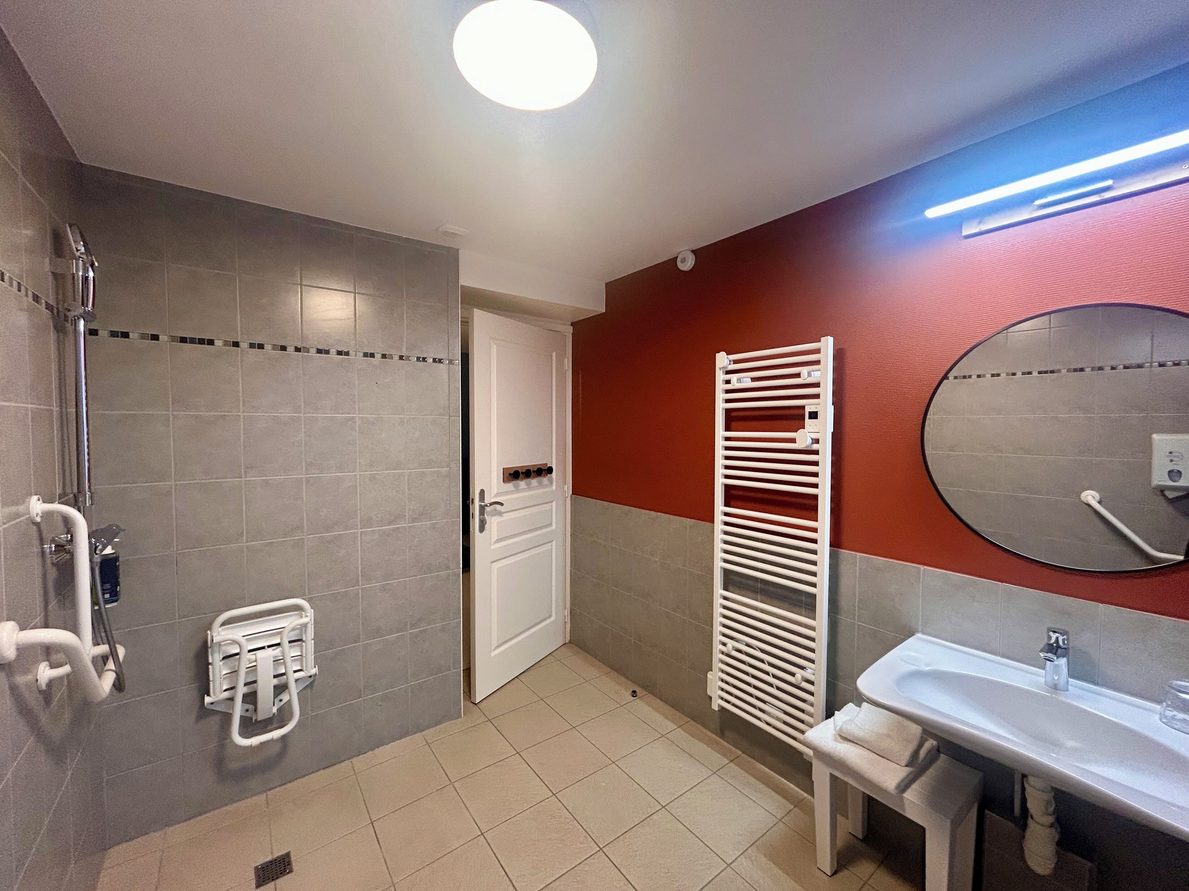 A bathroom with a shower, a toilet, a sink, and a towel rack.