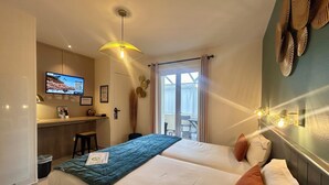 Une chambre d’hôtel avec deux lits, un bureau avec un ordinateur, une télévision et un balcon équipé d’une table et de chaises.