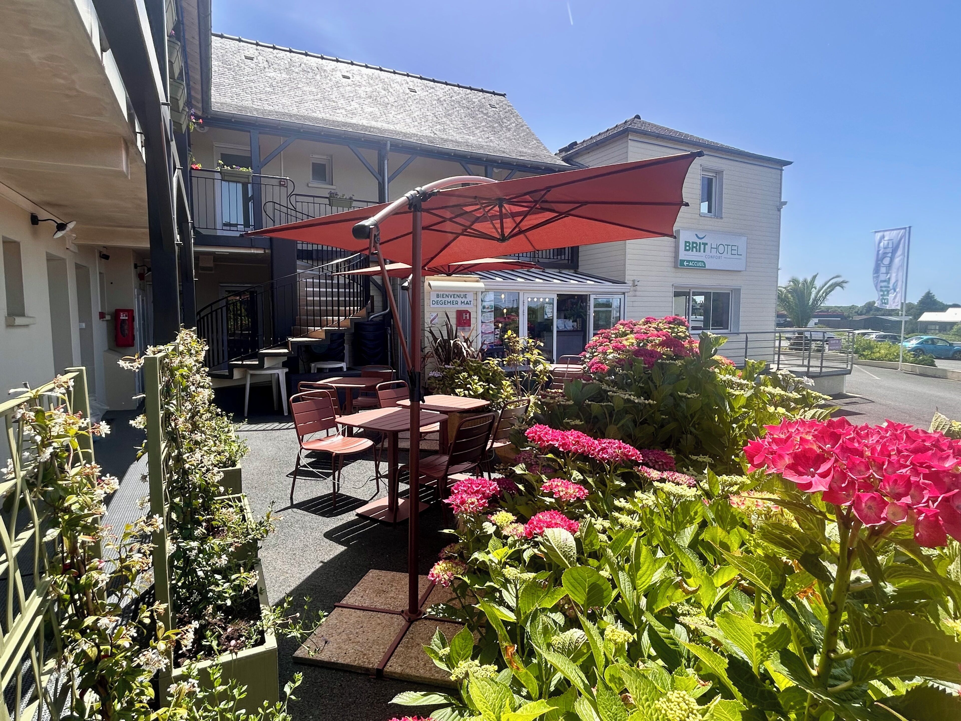 An outdoor seating area with tables and chairs, a staircase, and a building labeled 'BRIT HOTEL' in the background.