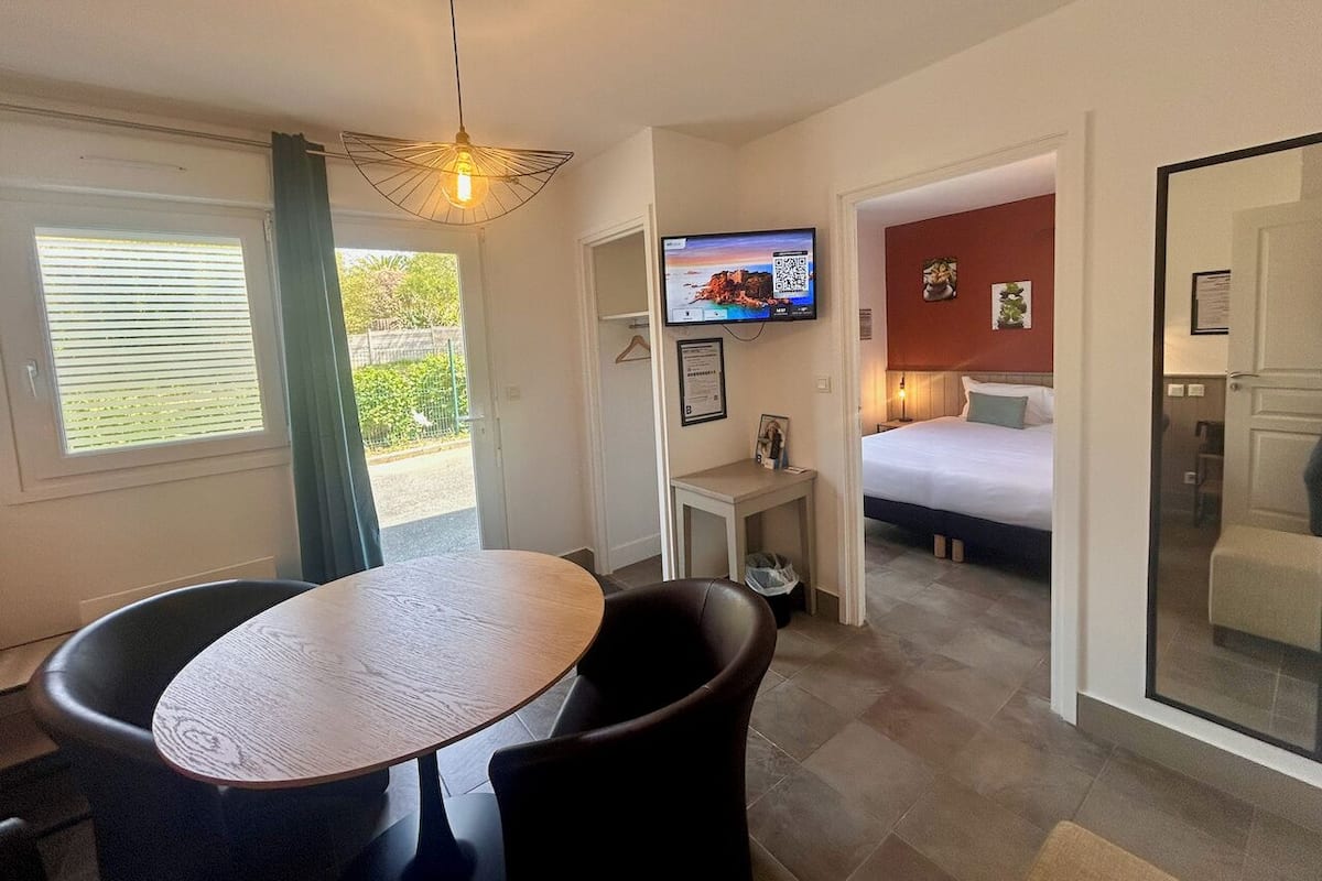 Een hotelkamer met een bed, een televisie, een eettafel en een stoel.