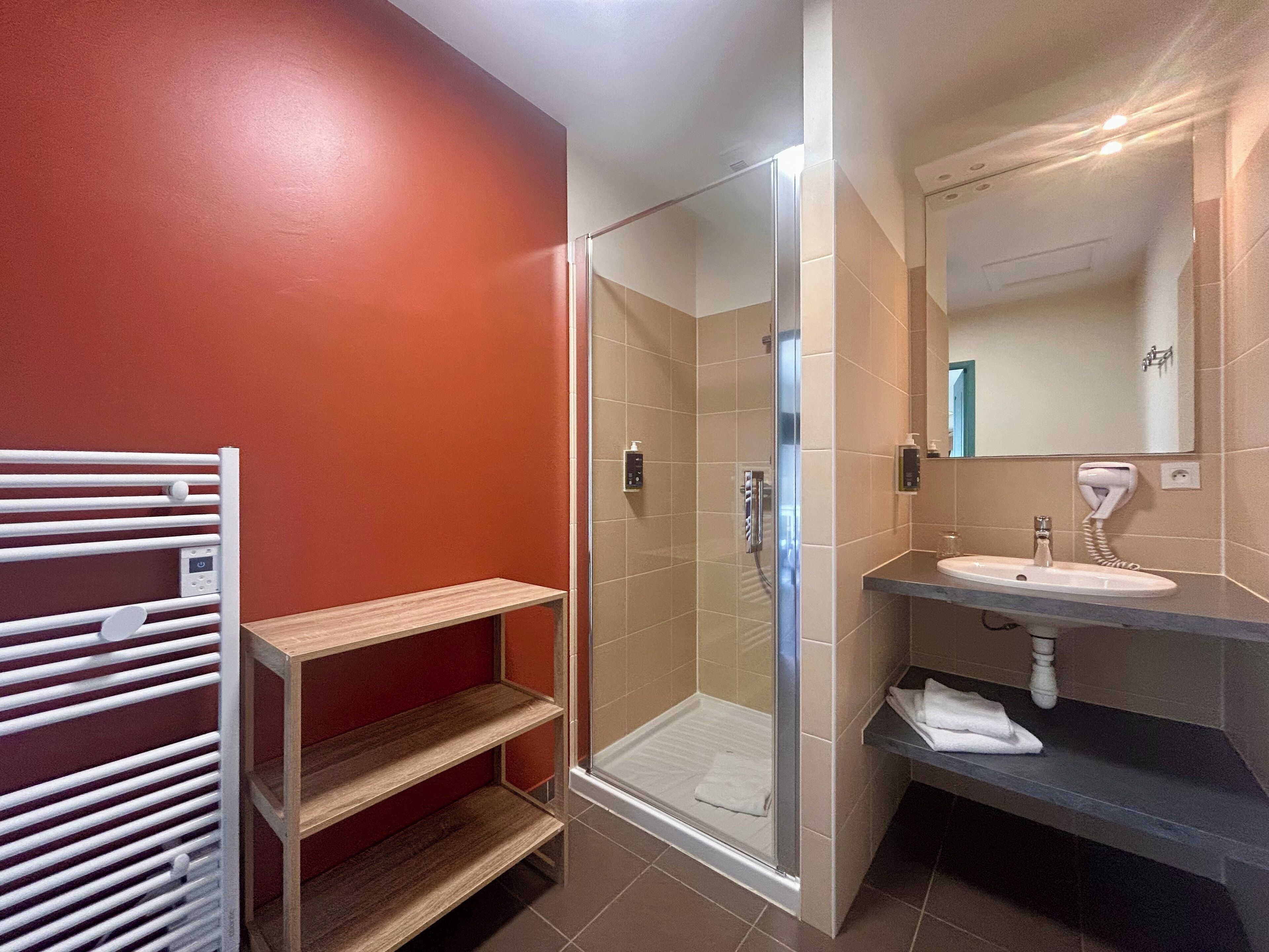 Een moderne badkamer met een douche met glazen wand, een witte handdoekhouder en een wastafel met spiegel erboven.