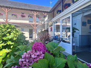 A hotel with a balcony, potted plants, and a visible room entrance.