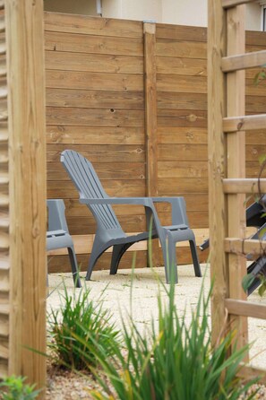A wooden fence with two plastic chairs and a ladder leaning against it.