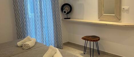 Une chambre d’hôtel avec un lit, un téléviseur fixé au mur, une petite table et un miroir.