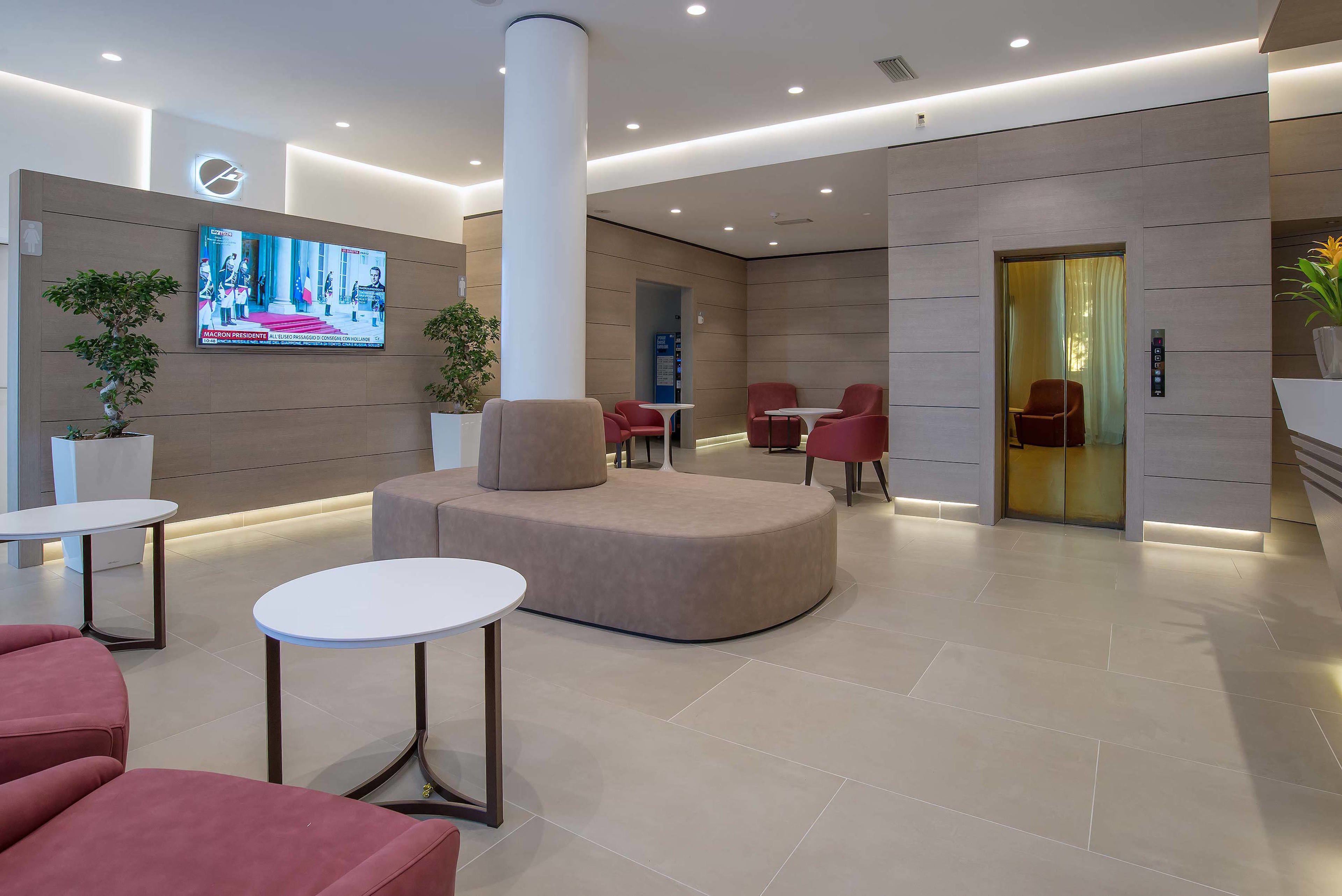 Een moderne lobby met een televisie, zithoeken en een receptiebalie.