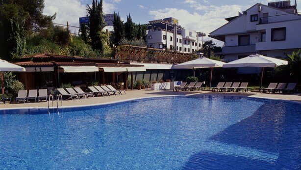 A swimming pool with lounge chairs and umbrellas, surrounded by buildings and greenery. - Hotel La Giocca (Rome)