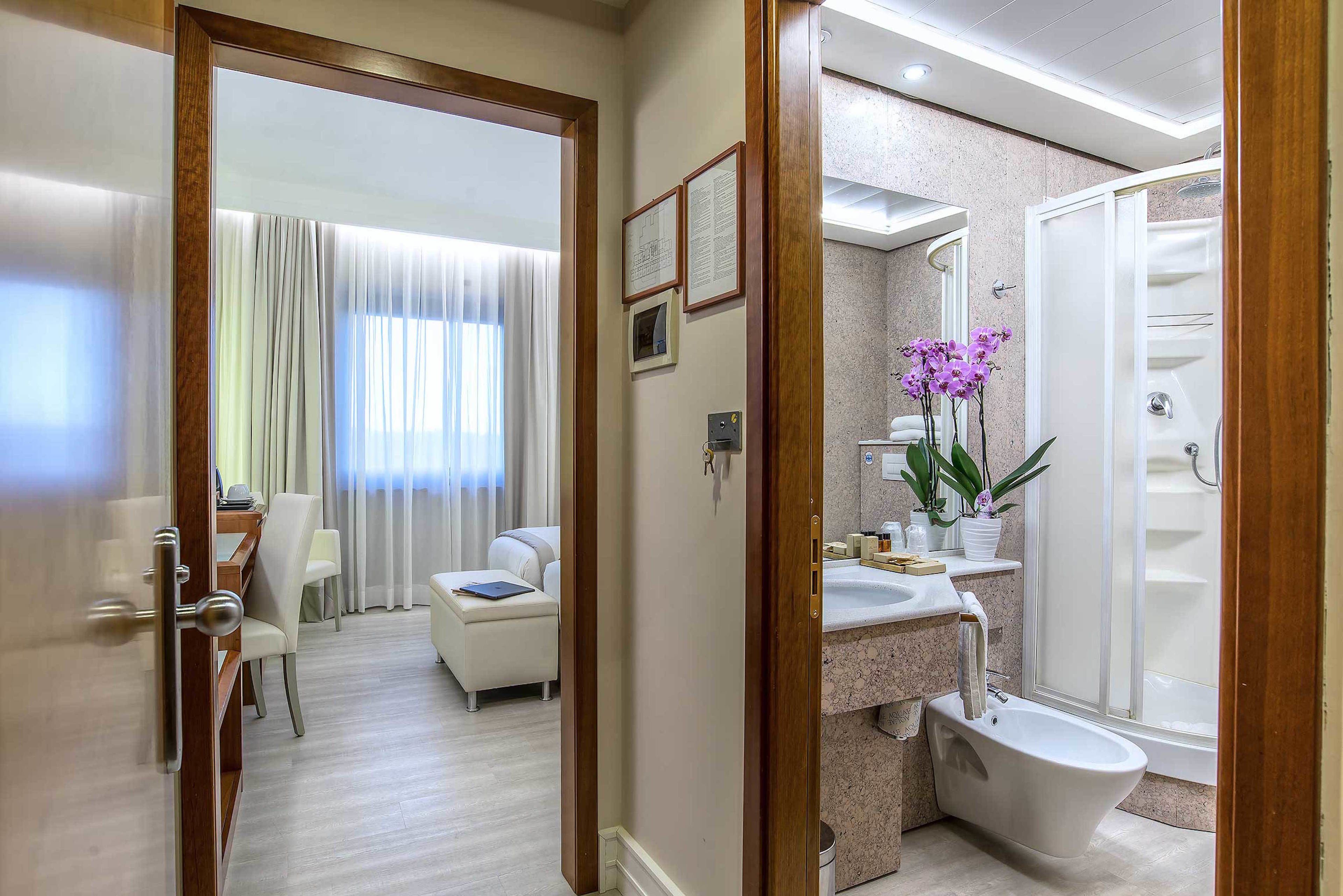 A hotel room with a bathroom featuring a bathtub, a sink, and a shower.