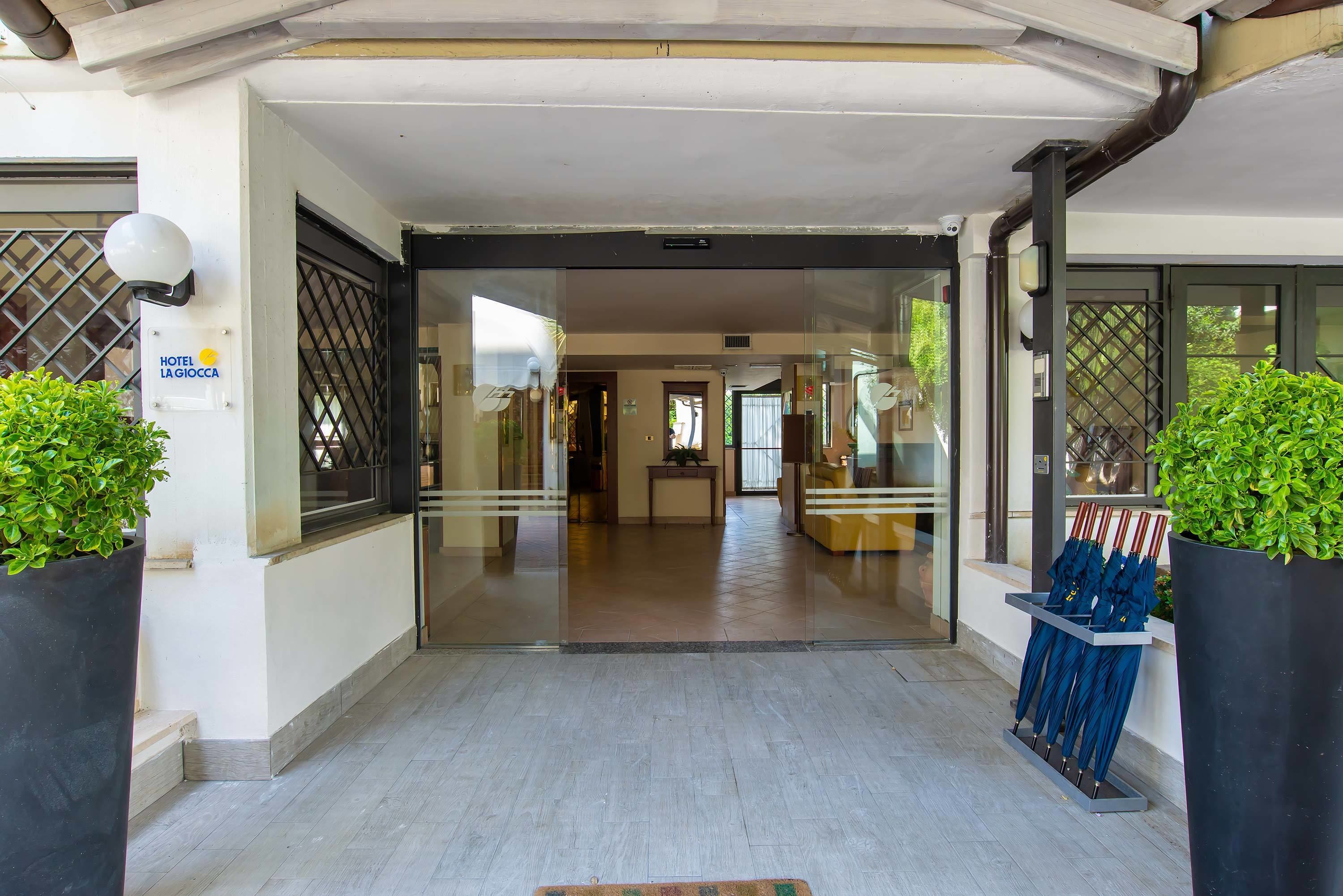 A hotel entrance with a glass door, potted plants, and a sign indicating the hotel name.