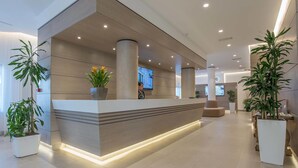 A modern reception area with a reception desk, potted plants, and a flat-screen TV. - Hotel La Giocca (Rome)