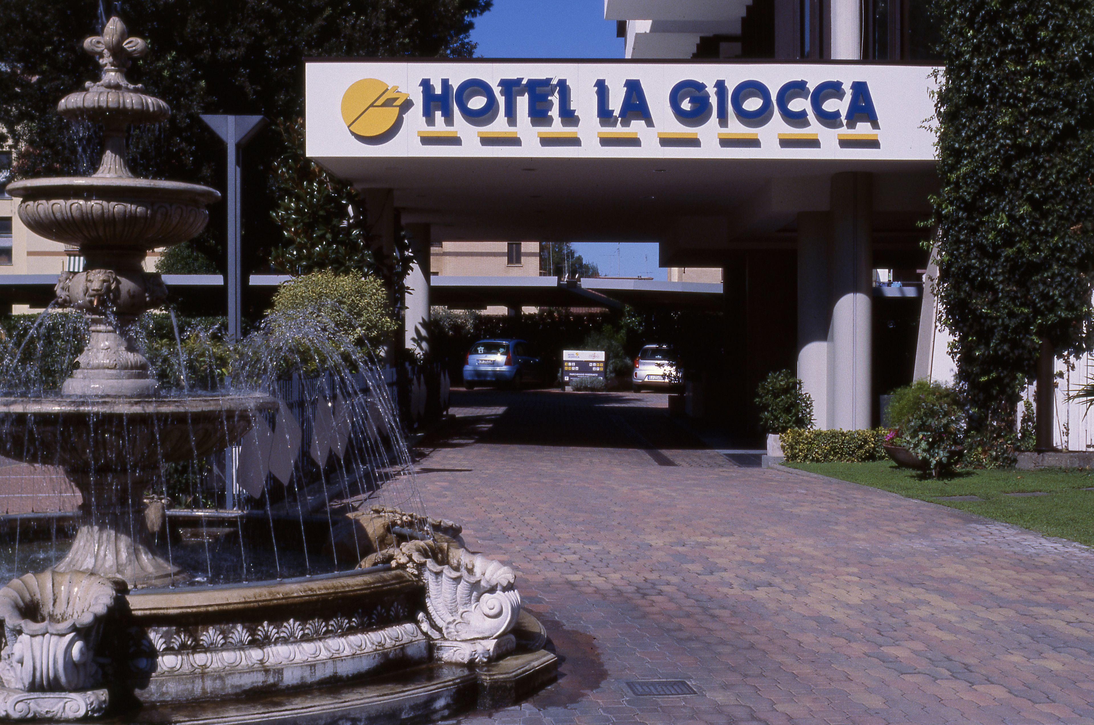 Entrada de un hotel con una fuente y un letrero que dice "HOTEL LA GIOCCA".